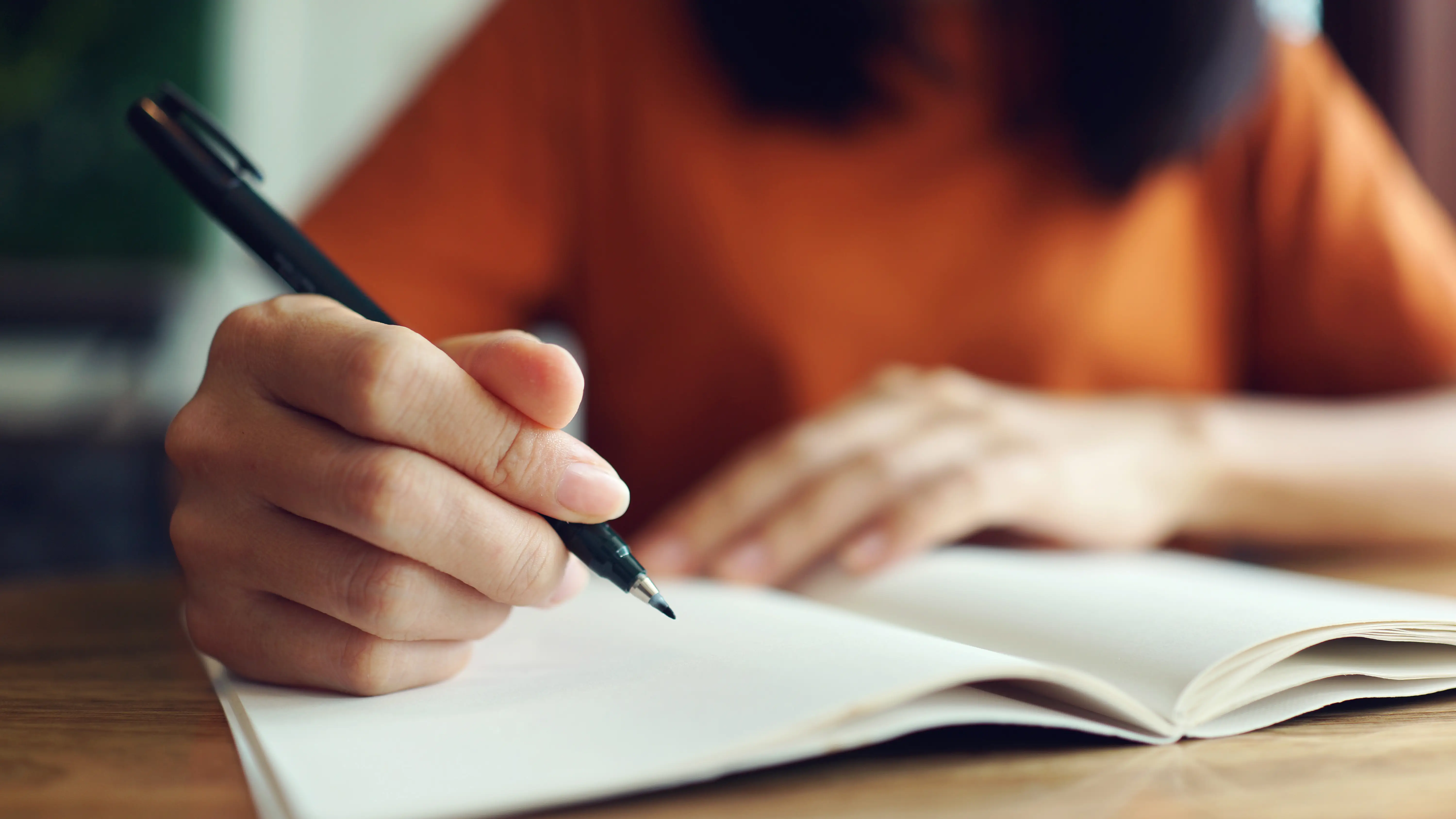 Mujer escribiendo a mano en un cuaderno Mujer escribiendo a mano en un cuaderno