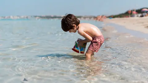 Niño jugando en la playa con agua cristalina Niño jugando en la playa con agua cristalina