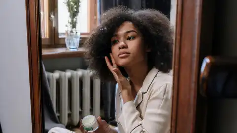 Preadolescente poniéndose una crema facial Preadolescente poniéndose una crema facial