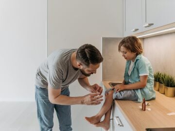 Padre curando una herida de su hijo