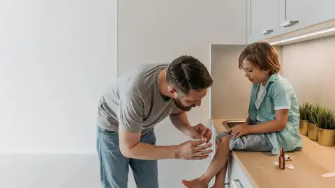 Padre curando una herida de su hijo Padre curando una herida de su hijo