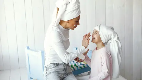 Madre aplicando cremas a su hija Madre aplicando cremas a su hija