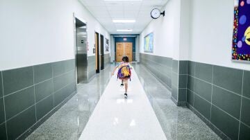 Niña corriendo por el pasillo de un colegio.