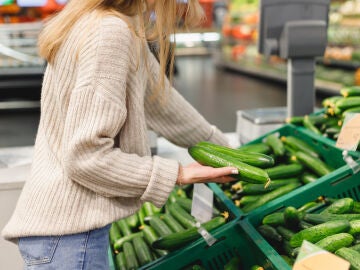 Mujer comprando pepinos en el supermercado