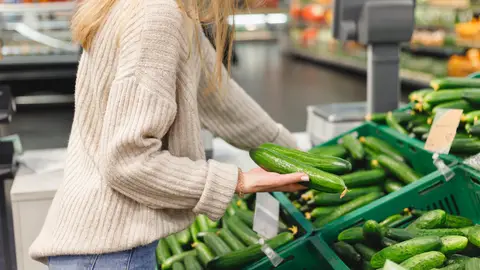 Mujer comprando pepinos en el supermercado Mujer comprando pepinos en el supermercado