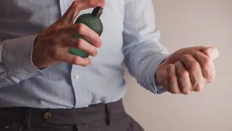 Hombre echándose perfume en la muñeca Hombre echándose perfume en la muñeca