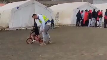 Un policía enseña a montar en bici a un niño migrante