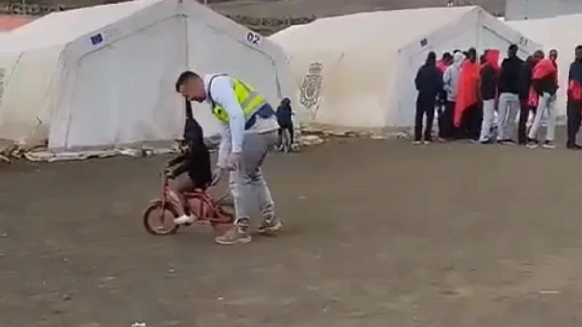 Un policía enseña a montar en bici a un niño migrante Un policía enseña a montar en bici a un niño migrante