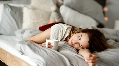 Mujer en la cama con un café Mujer en la cama con un café