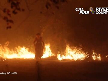 Una mujer huye a pie de las llamas de los incendios de California