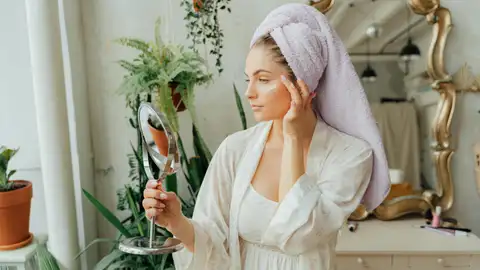 Una mujer con la piel radiante se mira al espejo Una mujer con la piel radiante se mira al espejo
