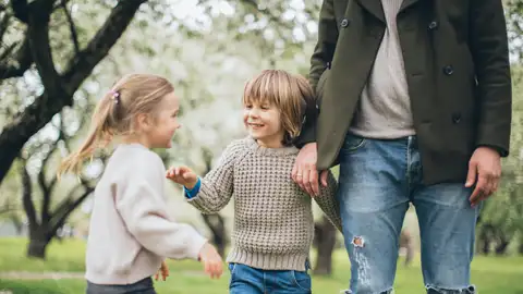 Un padre con sus dos hijos en un parque Un padre con sus dos hijos en un parque