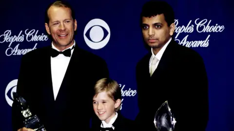 Bruce Willis, Haley Joel Osment y M. Night Shyamalan en el año 2000 Bruce Willis, Haley Joel Osment y M. Night Shyamalan en el año 2000