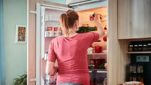 Mujer cogiendo algo de la nevera Mujer cogiendo algo de la nevera