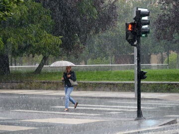 Una mujer se protege de la lluvia con un paraguas, en una fotografía de archivo