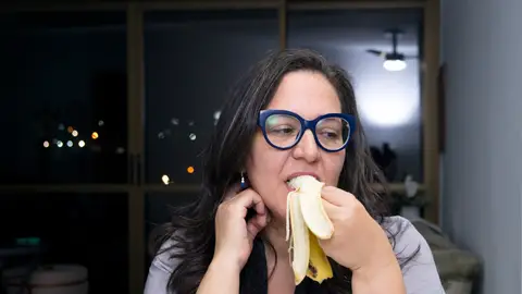 Una mujer comiendo fruta por la noche Una mujer comiendo fruta por la noche