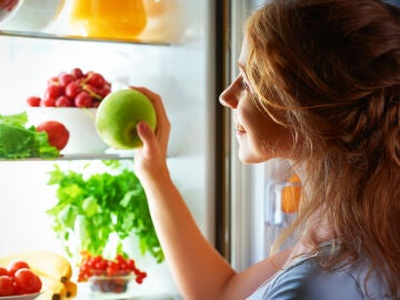 Una mujer cogiendo fruta de la nevera