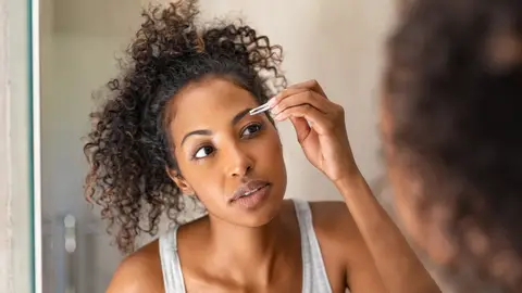 Mujer depilándose las cejas Mujer depilándose las cejas