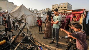 Ni&ntilde;os ante los restos calcinados de unas tiendas en el campamento de Deir al Balah