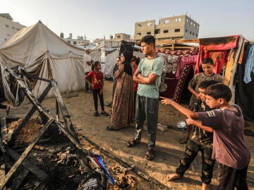 Niños ante los restos calcinados de unas tiendas en el campamento de Deir al Balah