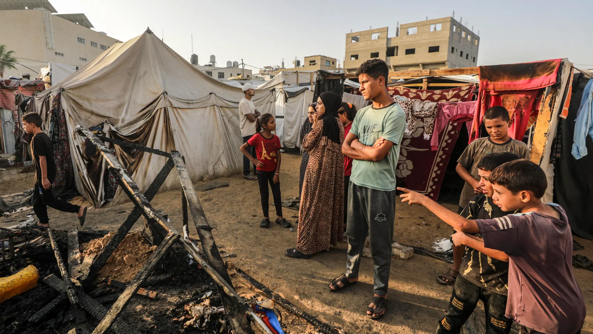 Niños ante los restos calcinados de unas tiendas en el campamento de Deir al Balah Niños ante los restos calcinados de unas tiendas en el campamento de Deir al Balah