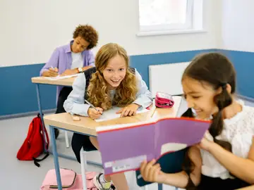 Dos niñas en el colegio se divierten con un libro. Dos niñas en el colegio se divierten con un libro.