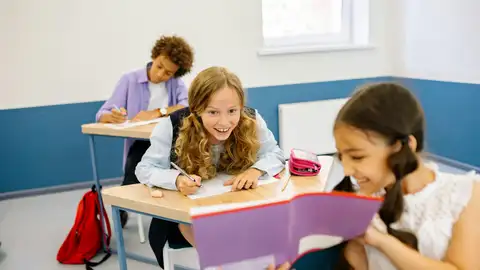 Dos niñas en el colegio se divierten con un libro. Dos niñas en el colegio se divierten con un libro.