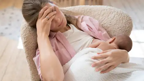 Una madre muy cansada da el pecho a su bebé recién nacido Una madre muy cansada da el pecho a su bebé recién nacido