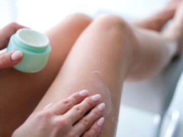 Una persona echándose crema en las piernas