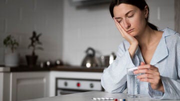 Una mujer con sueño se toma medicamentos