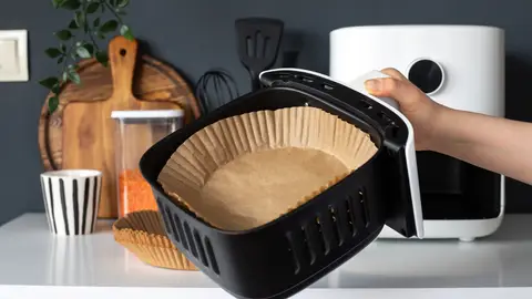 Una freidora de aire con papel de horno Una freidora de aire con papel de horno