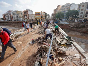 Decenas de voluntarios trabajan para despejar uno de los puentes de Paiporta