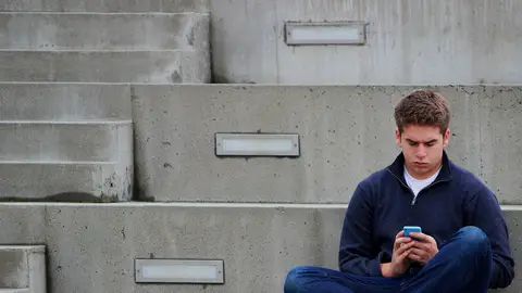 Imagen de archivo de un adolescente viendo el móvil Imagen de archivo de un adolescente viendo el móvil