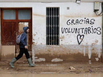 Un hombre camina junto a un graffitti que agradece la ayuda a los voluntarios 