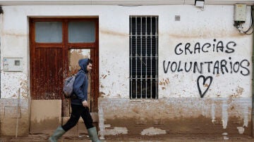 Un hombre camina junto a un graffitti que agradece la ayuda a los voluntarios 