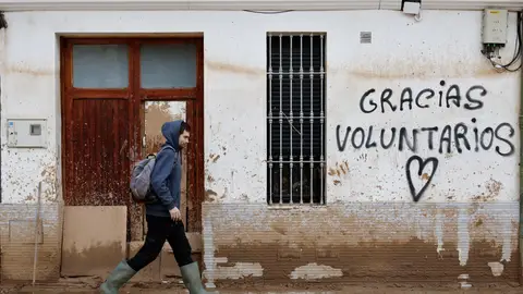 Un hombre camina junto a un graffitti que agradece la ayuda a los voluntarios Un hombre camina junto a un graffitti que agradece la ayuda a los voluntarios