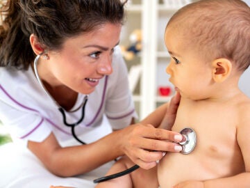 Una pediatra revisa la respiración de un bebé con el fonendoscopio.