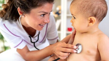 Una pediatra revisa la respiración de un bebé con el fonendoscopio.