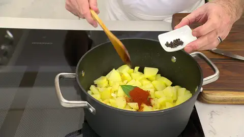 Añade la hoja de laurel, el pimentón y los granos de pimienta, y mezcla bien Añade la hoja de laurel, el pimentón y los granos de pimienta, y mezcla bien