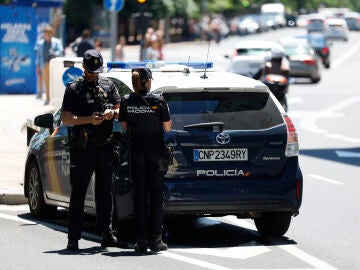 Imagen de archivo de una pareja de agentes junto a un coche de la Policía Nacional.