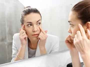 Una mujer con ojeras se mira en el espejo Una mujer con ojeras se mira en el espejo