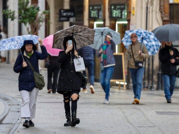 Imágenes de varias personas en la calle bajo la lluvia. 