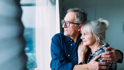 Una pareja madura observa por la ventana Una pareja madura observa por la ventana