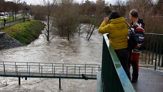 Dos personas observan en caudal del r&iacute;o Manzanares este viernes en Madrid