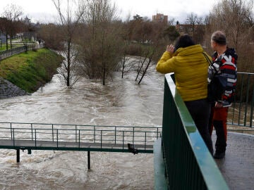 Dos personas observan en caudal del río Manzanares este viernes en Madrid