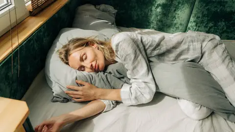 Una mujer durmiendo abrazada a una almohada Una mujer durmiendo abrazada a una almohada