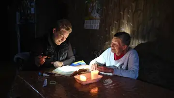 Imagen de archivo de dos personas en una casa con velas y una linterna. Imagen de archivo de dos personas en una casa con velas y una linterna.