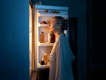 Mujer abriendo la nevera a oscuras Mujer abriendo la nevera a oscuras