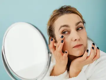 Mujer poniéndose crema en las ojeras Mujer poniéndose crema en las ojeras
