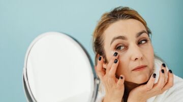 Mujer poniéndose crema en las ojeras